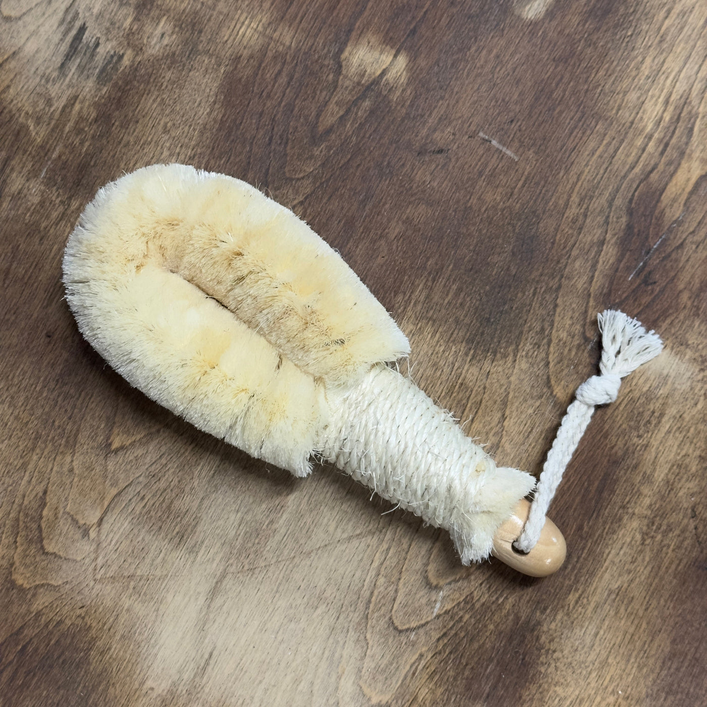 Natural fiber brush with a wooden handle on a wooden surface