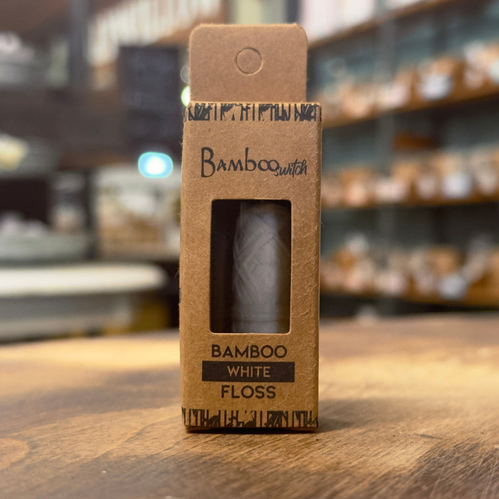Bamboo White Floss packaging on a wooden surface with a blurred store background